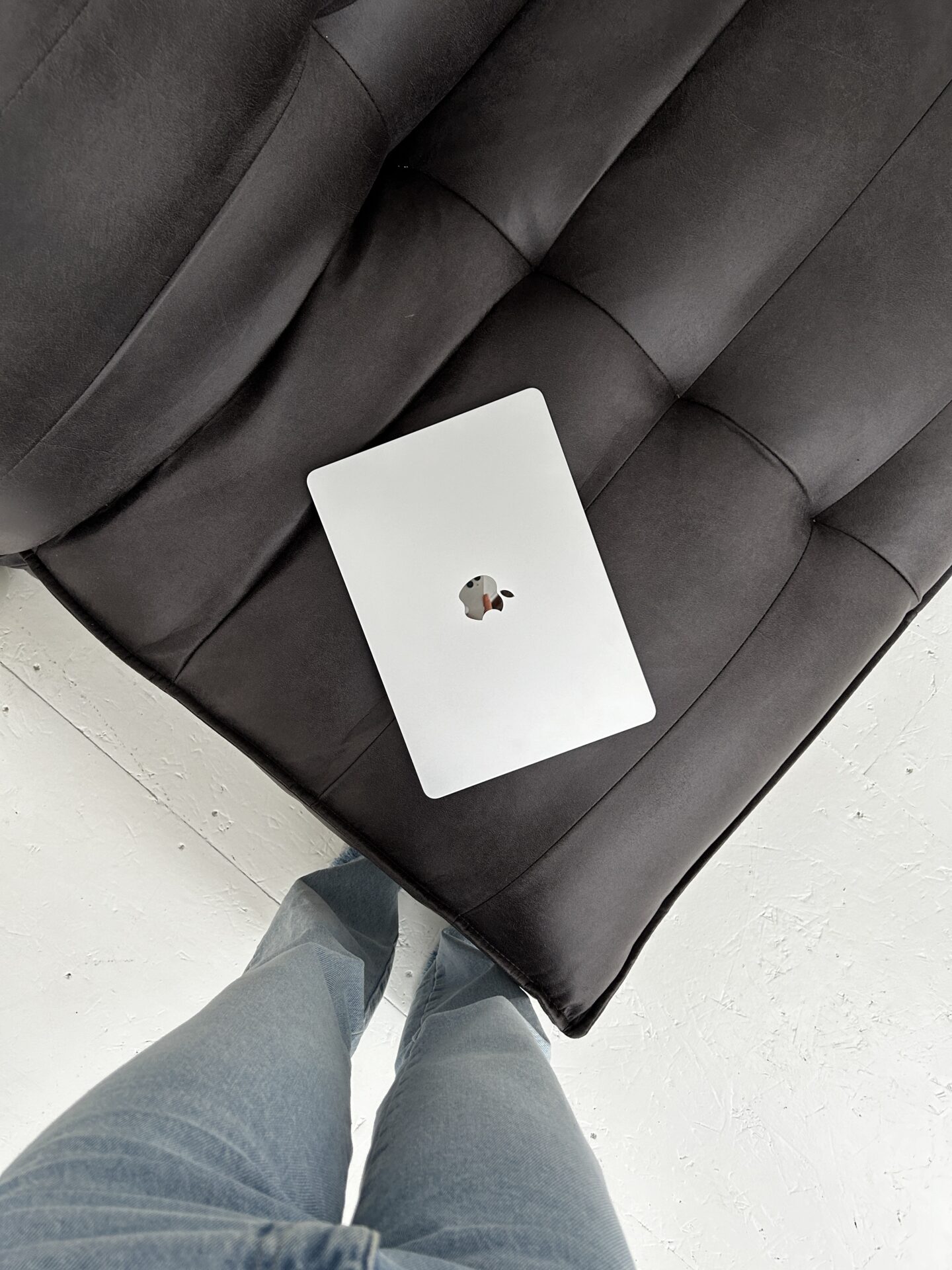 pov of woman standing looking down at closed macbook on black chair